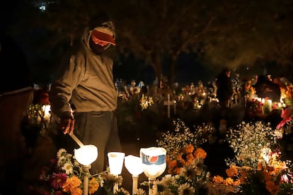 Un hombre enciende velas sobre la tumba de uno de sus familiares, en el panteón municipal de Xochitlán de los Santos, la madrugada del 2 de noviembre de 2023. 