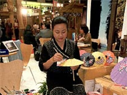 Artesana tailandesa pintando sombrillas de papel en la reciente Feria de Turismo (Fitur) celebrada en Madrid.