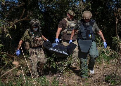 Militares ucranios trasladan el cadáver de un soldado ruso en una bolsa en la localidad de Blahodatne, en la región de Donetsk, ayer viernes.