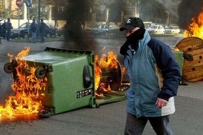 Un trabajador de los astilleros de Izar pasa junto a una barricada incendiada, ayer, en Gijón.