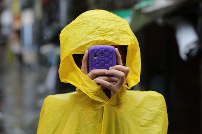 Un filipino cubierto con un impermeable hace fotos con su teléfono en Quezon, por donde ha pasado el tifón Rammasun, en Filipinas. 16 de julio de 2014.