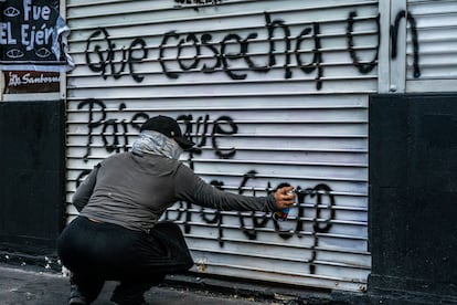 Una mujer pinta un edificio a manera de protesta.