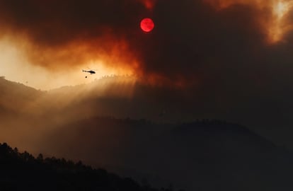 Un helicóptero arroja agua sobre las llamas cercanas a Mombeltrán, en Ávila, este martes.