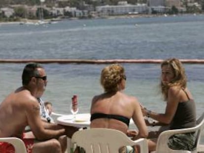 Unos turistas conversan en una terraza en la playa ibicenca de Talamanca.