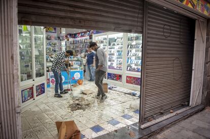 Tres dependientes limpian el suelo de una tienda afectada tras la fuerte lluvia que afectó anoche en el barrio barcelonés del Raval.