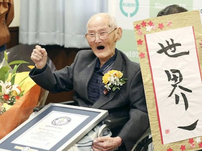 Watanabe, al recibir la distinción de Guinness a su récord, junto a una caligrafía suya en japonés.