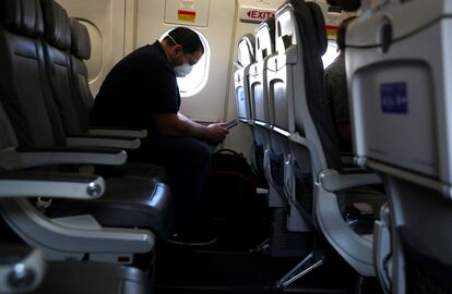 Un pasajero de un avión con mascarilla.