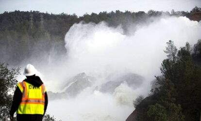 Un operario observa como el agua desciende por la presa de Oroville, California.