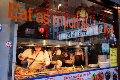 Bajo un cartel que reza "Come tanto como quieras", varias personas se sirven comida en un buffet libre de un restaurante chino en Londres.