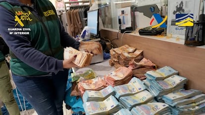 Un agente de la Guardia Civil, junto a parte de los fajos de billetes intervenidos en la operación, en una imagen facilitada por Europol.