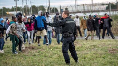 Un gendarme davant un grup de migrants a Calais.