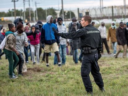 Un gendarme ante un grupo de migrantes en Calais.