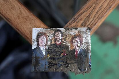 Los rostros de tres personas, cubiertos por el lodo, en una fotografía recuperada de un apartamento de Kensennuma, japón.