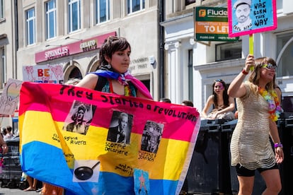 Una manifestante de la marcha del orgullo de Brighton (Reino Unido) de 2022 sostiene una bandera con las imágenes de las activistas Sylvia Rivera, Stormé DeLarverie y Marsha P. Johnson.