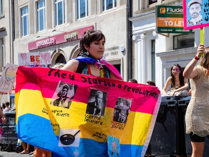 Una manifestante de la marcha del orgullo de Brighton (Reino Unido) de 2022 sostiene una bandera con las imágenes de las activistas Sylvia Rivera, Stormé DeLarverie y Marsha P. Johnson.