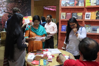 Varios visitantes de la Feria del Libro de Calcuta hojean folletos en el pabellón español.