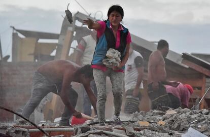 Un mujer retira escombros en busca de su marido en el barrio de Tarqui de la ciudad ecuatoriana de Manta.