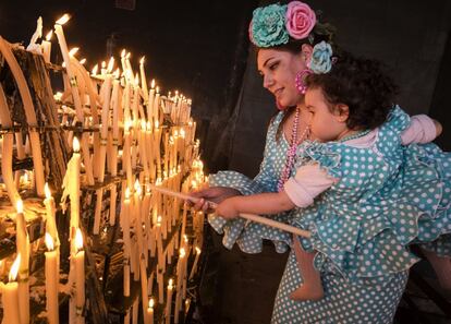 Una rociera coloca unas velas a la Virgen del Rocío en la aldea almonteña de El Rocío (Huelva), donde se ha celebrado la Misa de Romeros, una ceremonia que marca el inicio de este domingo de Pentecostés que culminará en la madrugada del lunes con el salto de la reja y la procesión de la 'Blanca Paloma' por las calles de la localidad.