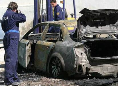 Un policía hace fotos del coche incendiado.