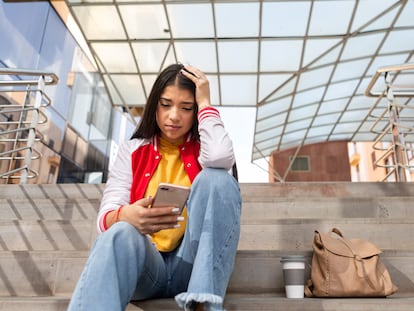 A young woman checks her cell phone.