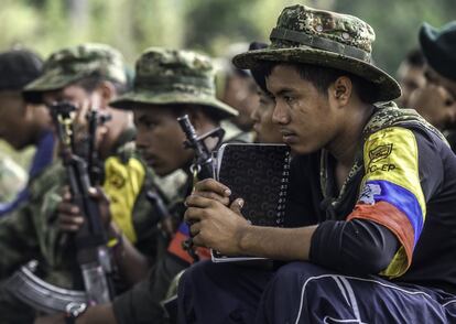 TO GO WITH AFP STORY by Hector Velasco
Revolutionary Armed Forces of Colombia (FARC) guerrillas listen during a "class" on the peace process between the Colombian government and their force, at a camp in the Colombian mountains on February 18, 2016. They still wear green combat fatigues and carry rifles and machetes, but now FARC rebel troops are sitting down in the jungle to receive "classes" on how life will be when they lay down their arms, if their leaders sign a peace deal in March as hoped.  AFP PHOTO / LUIS ACOSTA