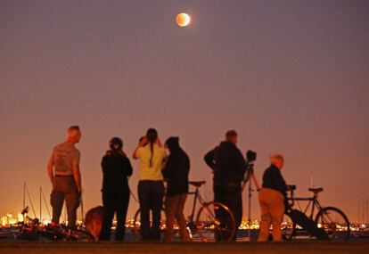 Observadores contemplan la 'Luna de sangre' en Melbourne durante el eclipse.