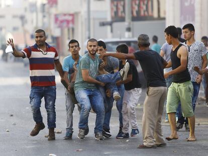 Un grupo de palestinos traslada a un herido, durante los enfrentamientos en la ciudad de Hebrón (Cisjordania).
