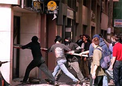 Un grupo de manifestantes ataca con una barra de hierro una sucursal bancaria.