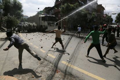 Jóvenes nepaleses, que desafían el confinamiento impuesto por el Gobierno por la epidemia de la covid-19, se enfrentan a la policía antidisturbios por no poder celebrar un acto religioso, en Lalitput (Nepal).