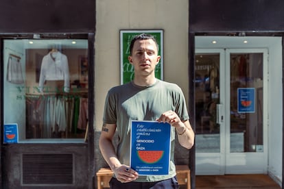 Carlos Guillén, dueño de la tienda de ropa 'Quality', posa con el cartel frente a su local en el barrio de Malasaña, Madrid.