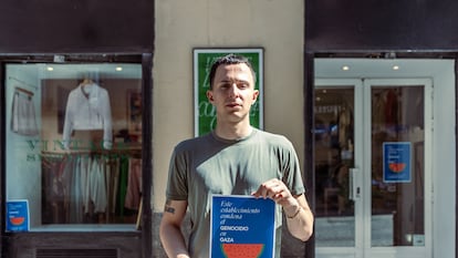 Carlos Guillén, dueño de la tienda de ropa 'Quality', posa con el cartel frente a su local en el barrio de Malasaña, Madrid.