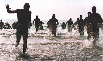 Varios participantes salen del agua tras la prueba de natación durante el triatlón disputado ayer en Valencia.