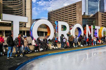Varios jóvenes esperan en una pista de hielo instalada en el centro de Toronto.