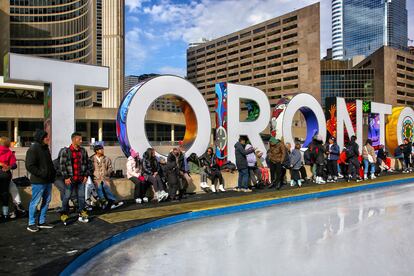 Varios jóvenes esperan en una pista de hielo instalada en el centro de Toronto.