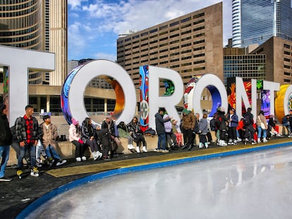 Varios jóvenes esperan en una pista de hielo instalada en el centro de Toronto.