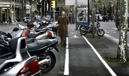 Un peatón, atrapado por el espacio reservado a los vehículos y el invadido por las motos, ayer, en la Diagonal de Barcelona.