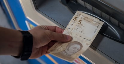 Uma pessoa saca duas notas de 5 bolívares digitais, a nova moeda venezuelana, nesta sexta-feira em Caracas.