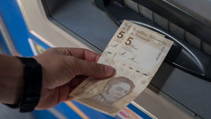 Uma pessoa saca duas notas de 5 bolívares digitais, a nova moeda venezuelana, nesta sexta-feira em Caracas.