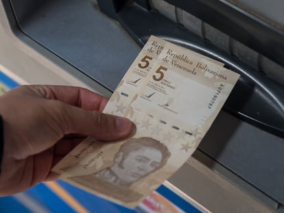 Uma pessoa saca duas notas de 5 bolívares digitais, a nova moeda venezuelana, nesta sexta-feira em Caracas.