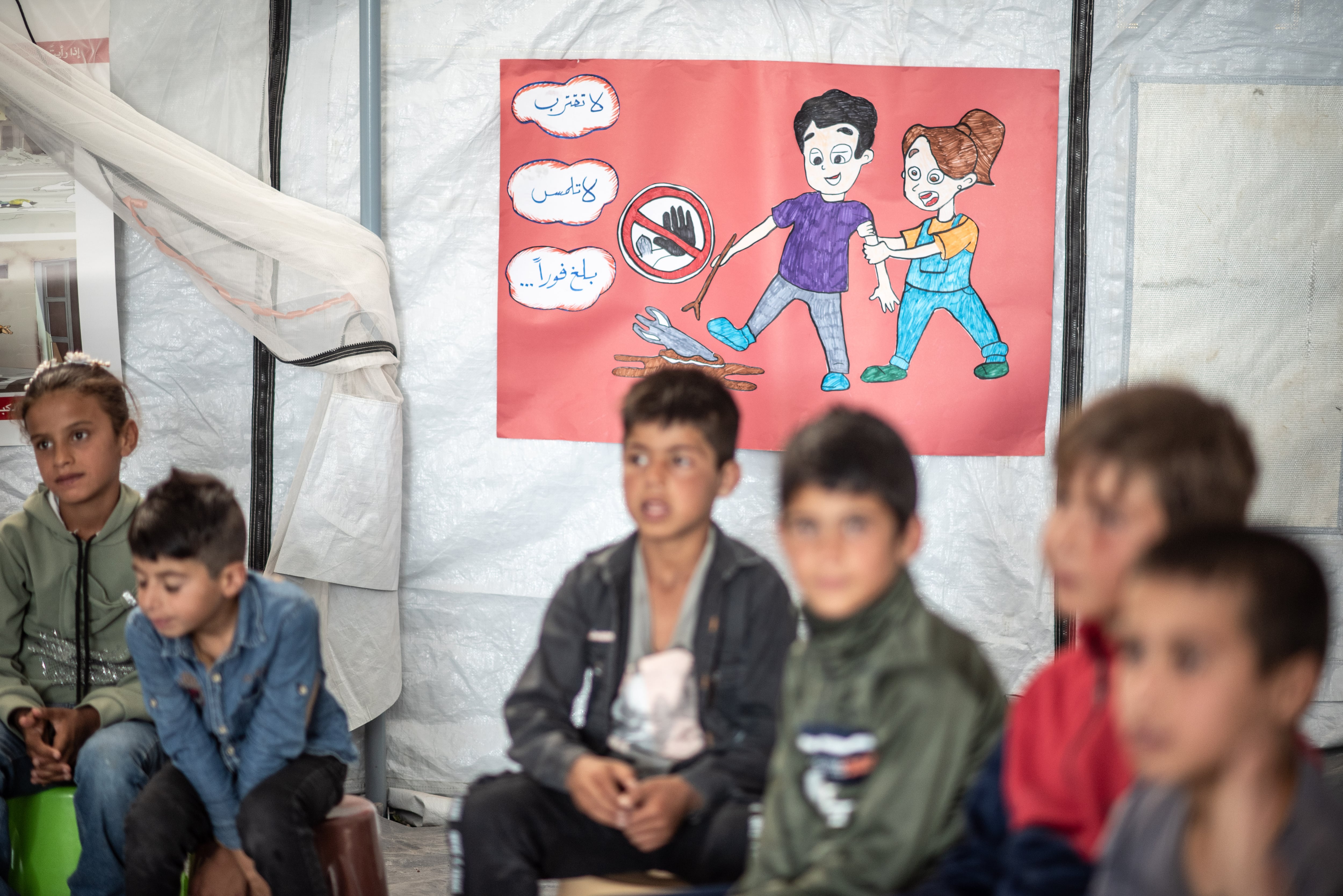 Niños de entre 10 y 12 años participan a un taller para identificar minas y explosivos sin detonar en una carpa habilitada como espacio de juego en el poblado de Mehin, en la provincia de Homs, el pasado 27 de julio.