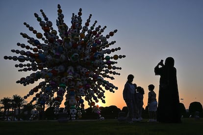 Una mujer toma fotografías de una obra de arte titulada 'Come Together', en Al-Rayyan, al oeste de Doha.