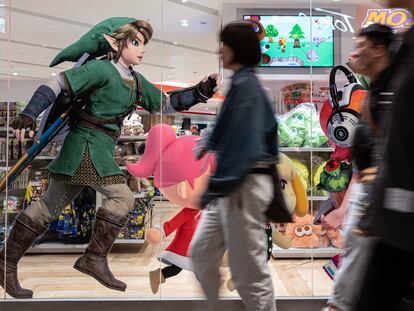 Viandantes caminan frente a un escaparate en Tokio que muestras publicidad del último 'Zelda'.