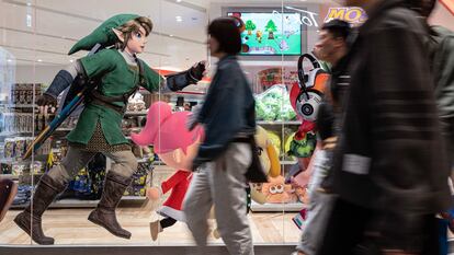 Viandantes caminan frente a un escaparate en Tokio que muestras publicidad del último 'Zelda'.