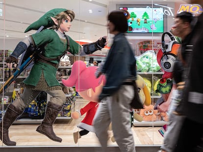 Viandantes caminan frente a un escaparate en Tokio que muestras publicidad del último 'Zelda'.