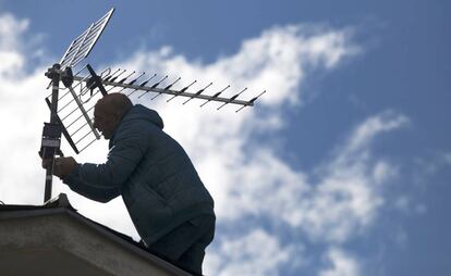 Un antenista cambia una antena antigua y resintoniza una nueva, 