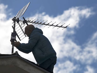 Un antenista cambia una antena antigua y resintoniza una nueva, 