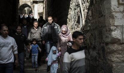 Fieles palestinos caminan junto a soldados armados en la Ciudad Vieja de Jerusal&eacute;n, el viernes