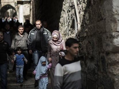 Fieles palestinos caminan junto a soldados armados en la Ciudad Vieja de Jerusal&eacute;n, el viernes