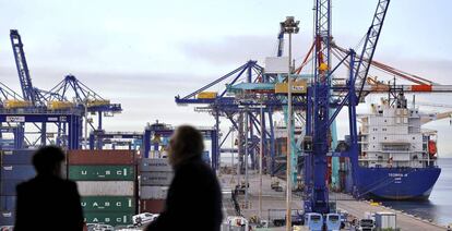 Dos personas observan, desde el edificio Veles e Vents de la Marina de Valencia, los trabajos de estiba en varios barcos.