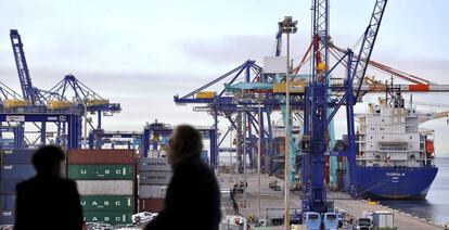 Dos personas observan, desde el edificio Veles e Vents de la Marina de Valencia, los trabajos de estiba en varios barcos. 